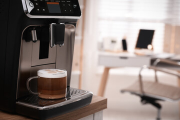 Modern espresso machine with glass cup of coffee on table in office. Space for text