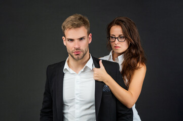 elegant man and woman in business look on black background, relations