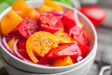 Salad with fresh vegetables, colorful tomatoes, onions and spices. Healthy food. Close-up 