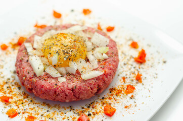 Beef steak tartare with raw egg yolk and onion with tomato
