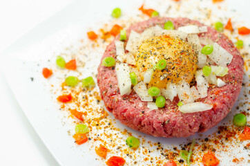 Fototapeta na wymiar Beef steak tartare with raw egg yolk and onion with tomato