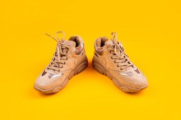fashionable sportive sneakers with laces on yellow background, fashion