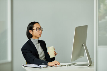 Minimal side view portrait of elegant Asian businessman using computer while working in private...