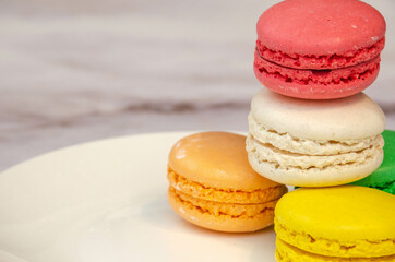 Colored sweet macaroons folded in a tower and located on a white plate