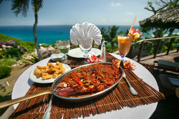 Exotische Speisen und Getränke auf Tisch mit Aussicht auf das Meer, Seychellen