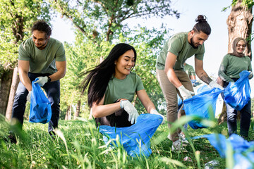 Multiethnic group of volunteers with garbage bags cleaning city park. - Powered by Adobe