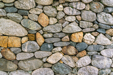 Background of stones. A wall of multicolored stones. The masonry is made of untreated stones. A wall of large stones.