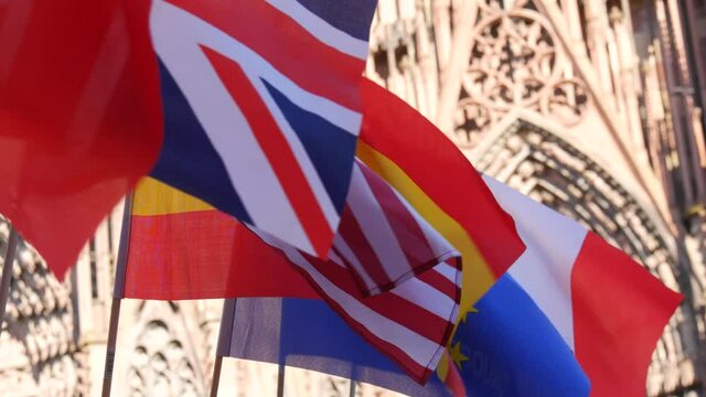 A row of European and American flags of Italy, France, Spain, the European Union against the background of Strasbourg Cathedral in France