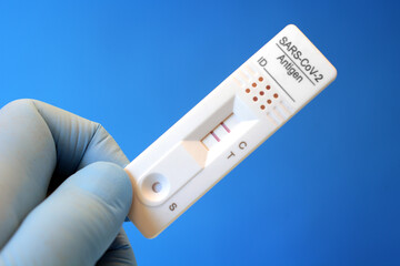 Doctor in a testing centre shows a rapid antigen test with a positive result for Corona or a...