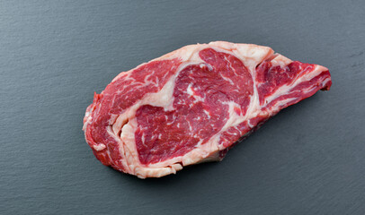 Fresh Black Angus Rib Eye Steak Raw on a dark background.