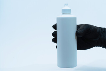 Man's hand in glove holds a white plastic bottle