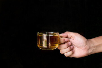 hand holding a cup of hot tea on a black background