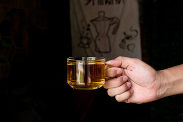 hand holding a cup of hot tea on a black background