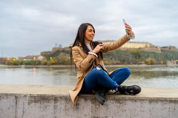 Woman taking selfie with her smartphone and drinking coffee takeaway