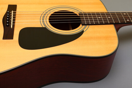 upper soundboard of an acoustic yellow guitar close-up on a gray background