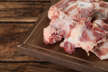 Cutting board with raw chopped meaty bones on wooden table. Space for text