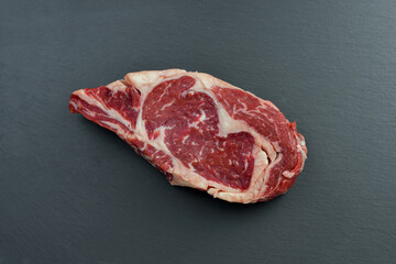 Fresh Black Angus Rib Eye Steak Raw on a dark background.