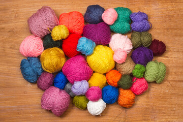 Variedad de ovillos hilos de lana de diferentes colores sobre un fondo de madera. Vista superior y...