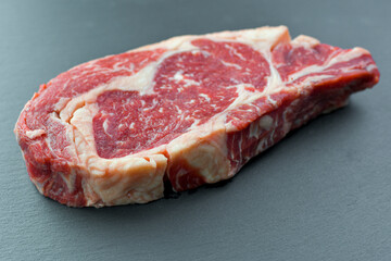 Fresh Black Angus Rib Eye Steak Raw on a dark background.