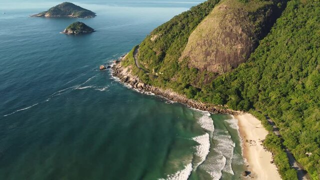 Aerial view of Prainha Beach, a paradise in the west side of Rio de Janeiro, Brazil. Big hills around. Sunny day at dawn. Greenish sea. Drone take.