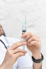 A doctor holding an injection syringe in his hand on white office 