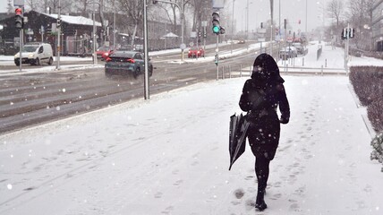 A girl with walks down the street during a heavy snowfall