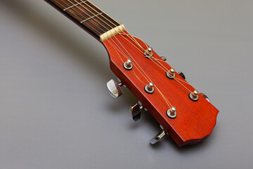 guitar headstock with metal pegs on a gray background