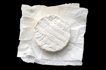 Brie cheese in craft white paper isolated on black background. Camembert cheese top view