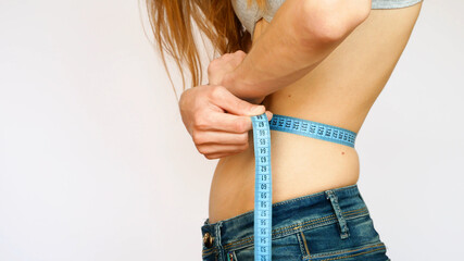 A very beautiful girl with a fantastic body measures the waist