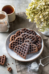 Chocolate waffles in the shape of a heart in ceramic plate on textured background, still life for...