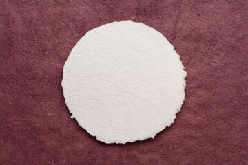 circular sheet of blank white watercolor paper against textured handmade bark paper