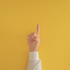 man hand with one finger. number one on the table against yellow background with copy space. minimalism. flatlay