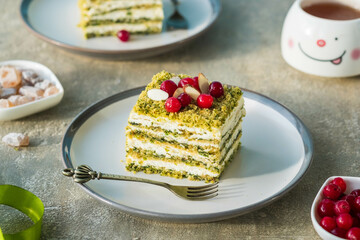 Dessert, sliced spinach cake with sour cream or cream cheese cream on a ceramic plate on a gray concrete background. Dessert recipes.