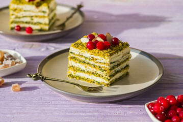 Dessert, sliced spinach cake with sour cream or cream cheese cream on a ceramic plate on a purple wooden background. Dessert recipes.