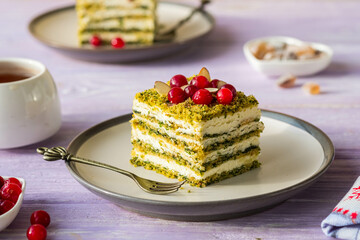 Dessert, sliced spinach cake with sour cream or cream cheese cream on a ceramic plate on a purple wooden background. Dessert recipes.