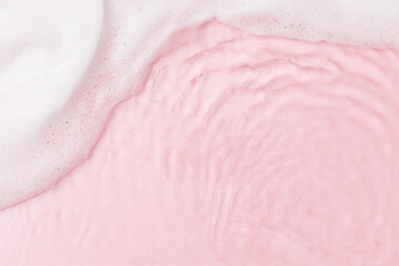Top view of pink transparent clear calm water surface. Texture with splashes, foam and bubbles....