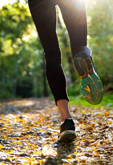 Running in green nature with the beautiful sunlight, closeup of the legs in motion