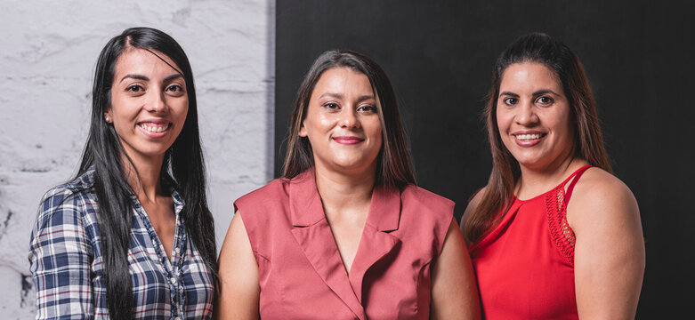 panorámica de tres mujeres latinas profesionales viendo a cámara