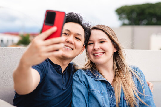 pareja multirracial haciendo una fotografía con un celular muy feliz