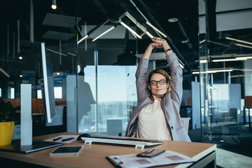 business owner woman resting during working hours puts her hands behind her head, thinks about business plans, works in a modern office
