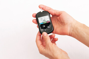 Close-up of the hands of a woman using a glucose meter to measure blood sugar isolated on a white background. Checking blood sugar level by glucometer for diabetes testing. High result, above the norm - obrazy, fototapety, plakaty