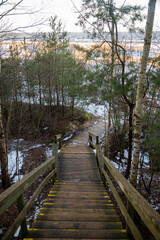 Obraz premium Wooden stairs on the footpath by the sea with yellow warning signs in winter.