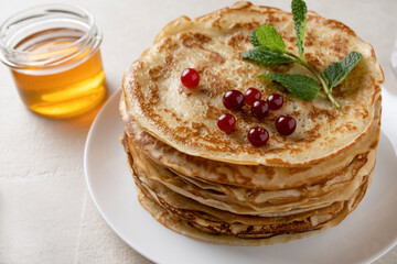 Shrovetide pancakes are stacked on the wooden plate. Thin pancakes with a crispy crust.  Pancakes for breakfast and Shrovetide.. Food background.