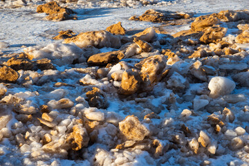 Fototapeta na wymiar Baltic Sea on wintertime with broken ice cracks. Large pieces of floating ice driven into the seaside. Pack Ice builds up the icebergs.