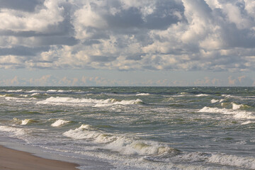 Beneath shredded clouds the last waves of a leaving storm are breaking against the shore of the Curonian Spit in Lithuania
