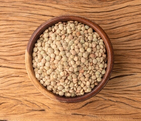 Raw lentils in a bowl over wooden table