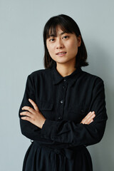 Vertical waist up portrait of young Asian businesswoman looking at camera
