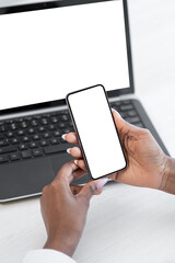 Online shopping. Mobile technology. Secure payment. App advertisement. Woman hands using phone blank mockup copy space screen at laptop.