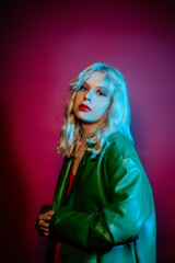 Girl in a stylish green coat on a pink background. Blonde with short hair make up in sparkles. Style and fashion, grunge style.