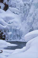 Stones with snow caps and ice in the water of frozen river in winter.